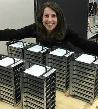 Katie Bouman, que participou da pesquisa que fotografou um buraco negro pela primeira vez, mostra a quantidade de HDs necessária para armazenar as informações da pesquisa / Foto: Reprodução MIT